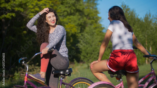 Two young cyclists communicate and laugh on a Cycling trip in the Park, on a Sunny summer day