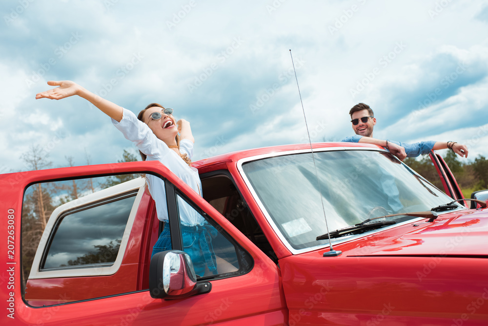 cheerful couple of travelers in red jeep cheerful couple of travelers in red jeep