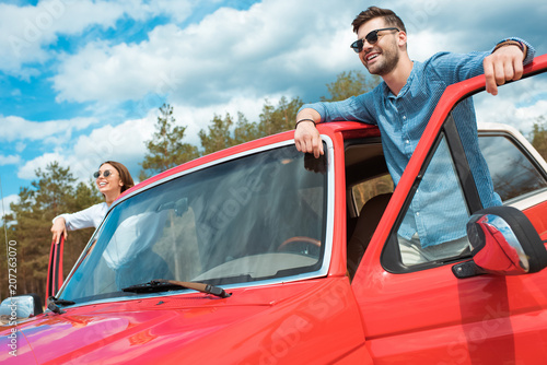 happy young couple of travelers in red jeep