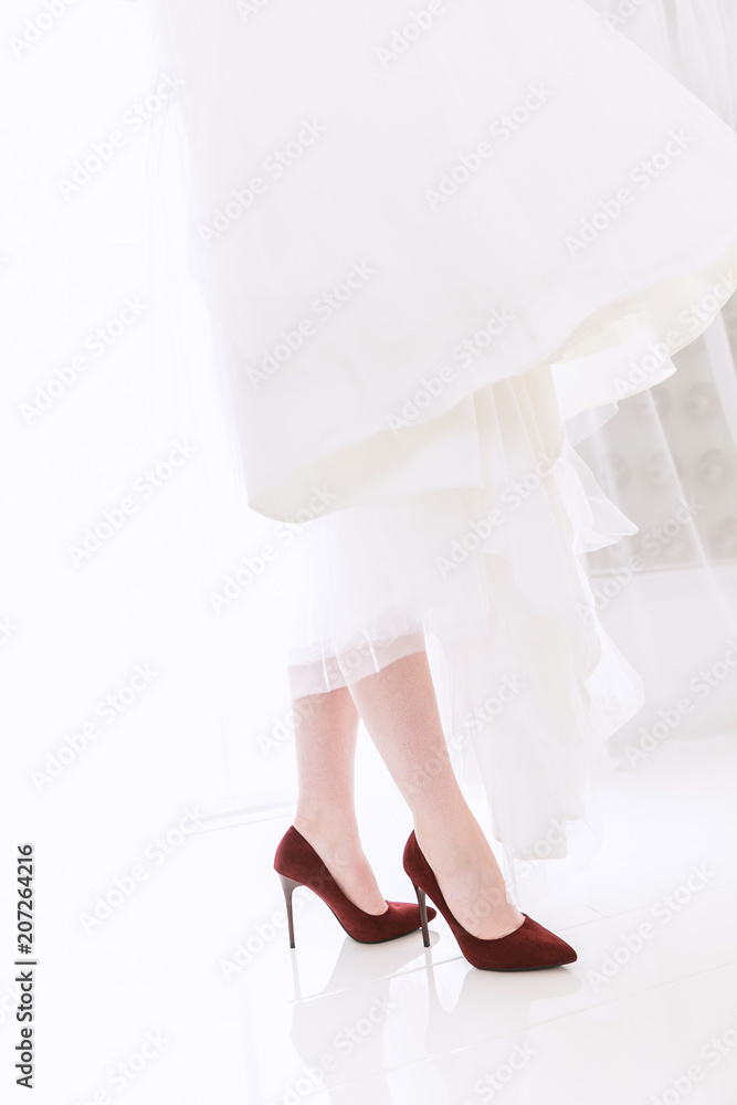 close-up of the bride's legs in red shoes. Reflection of the legs of a woman in shoes on tiles