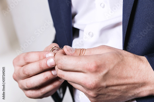 groom holds the wedding rings on the palm