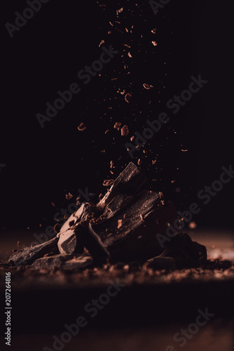 Valokuva close up shot of grated dark chocolate falling on pieces of chocolate on black b