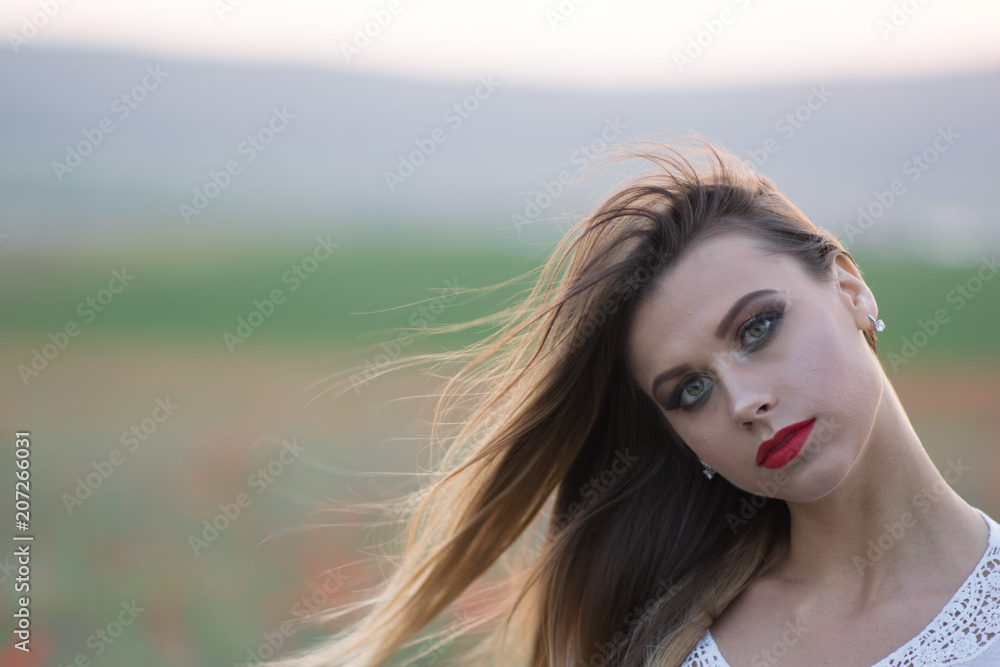 Fototapeta premium Pretty young blonde walking on a poppy fields