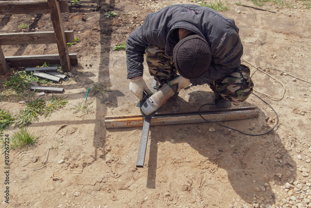 Worker cuts metal for doors at a construction site Worker cuts metal for doors at a construction site