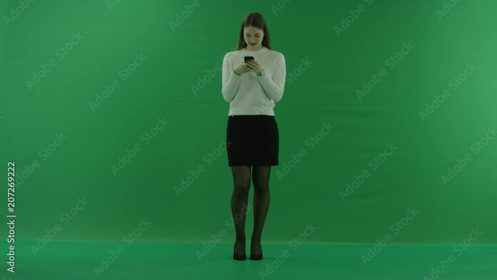 the girl is texting about something nice on the phone on green screen the girl is texting about something nice on the phone on green screen