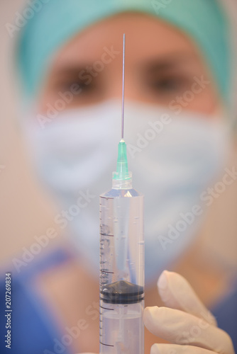 Close up of syringe held by masked medic