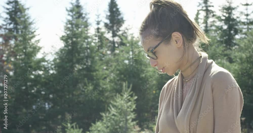 Young beautiful hip woman with forest in background turns and looks down towards dog Young beautiful hip woman with forest in background turns and looks down towards dog