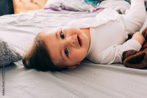 Funny baby lying on bed photo