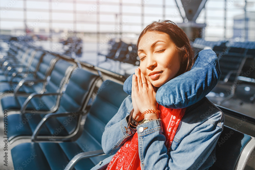 woman relaxing and sleeping with neck pillow at airport terminal