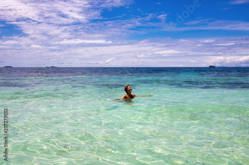 woman enjoy her bath in the beautiful water of exotic island, raja ampat archipelago © raffaellagalvani