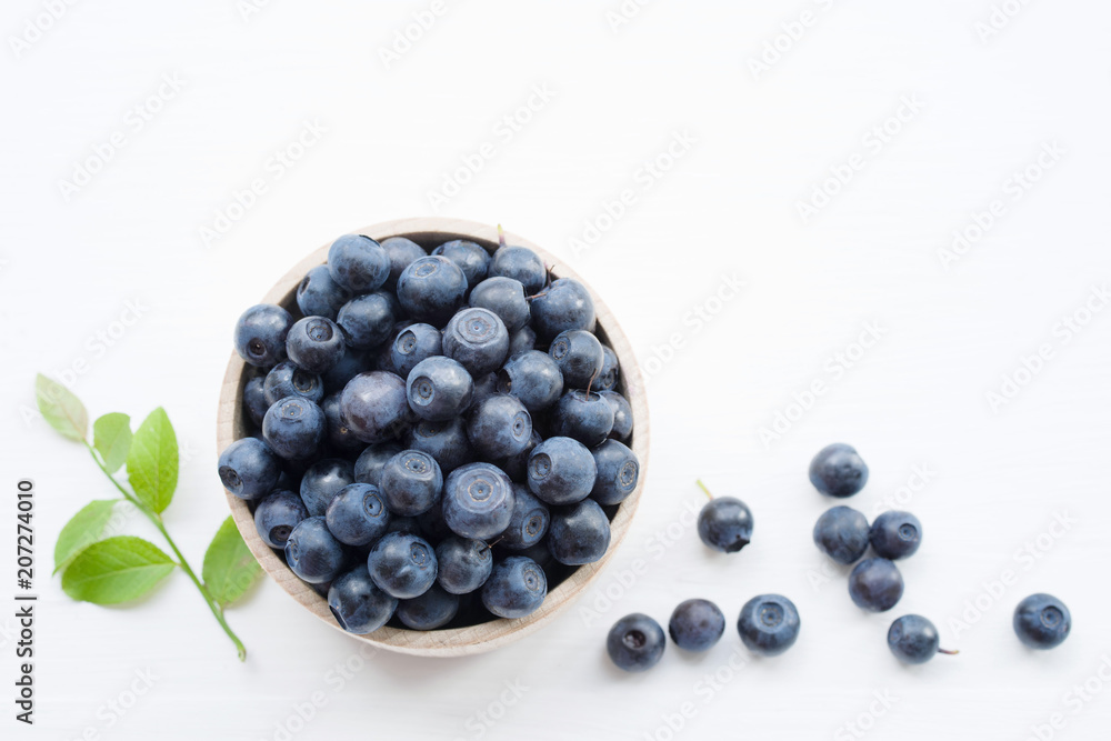 Fresh blueberries in a wooden cup on a light surface. Closeup, top view. Fresh blueberries in a wooden cup on a light surface. Closeup, top view.