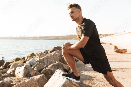 Fototapeta Naklejka Na Ścianę i Meble -  Portrait of a handsome sportsman doing stretching exercises
