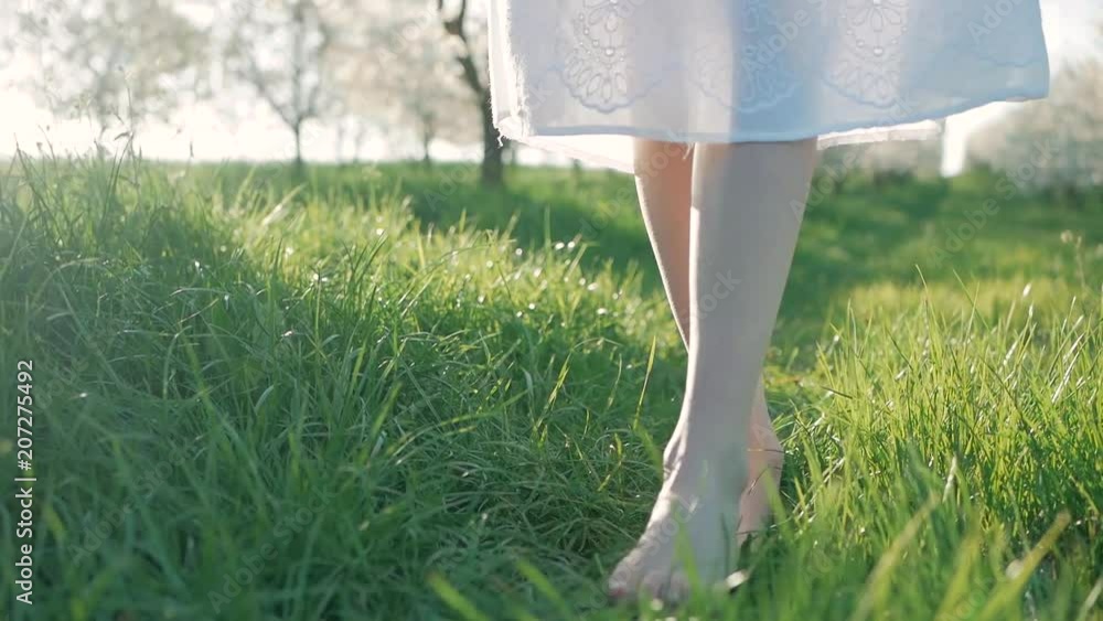 Slow motion shot of bare feet of young girl walking and running on green grass Slow motion shot of bare feet of young girl walking and running on green grass