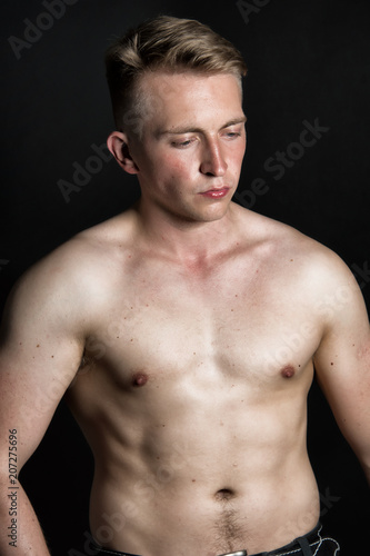 Young sexy guy and black background.