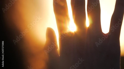 Girl looks at the sun through her hand