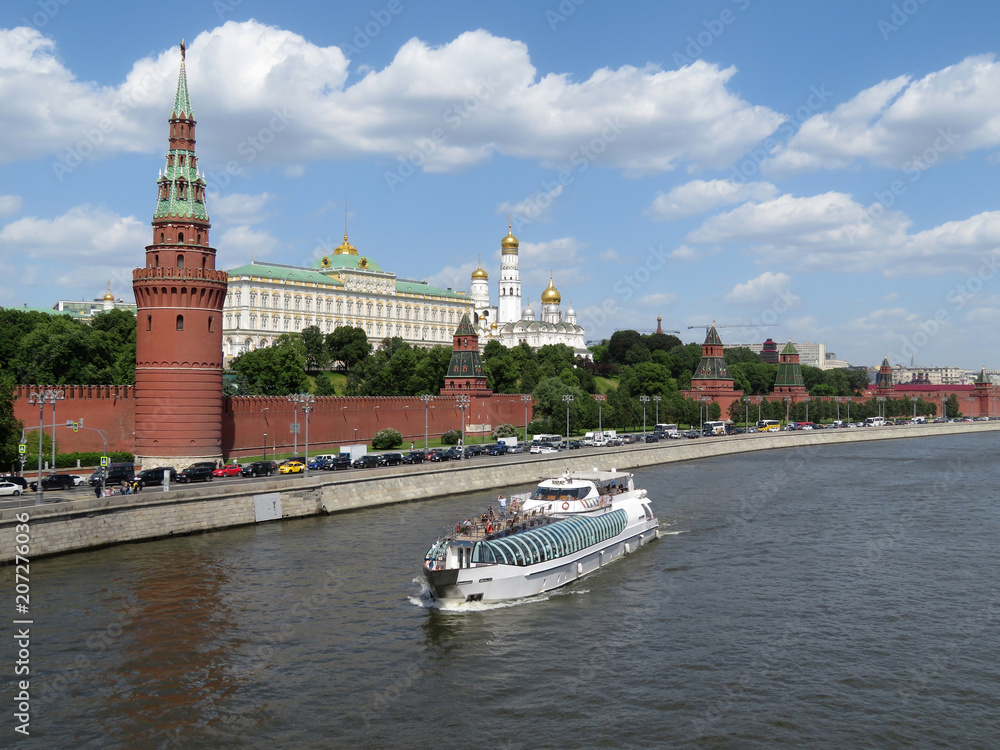 Obraz premium Tourist motor ship on the Moscow river on the background of the Kremlin towers. Kremlin embankment in summer, tourism in Russia