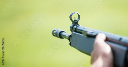 Shotgun in man' s hand. Front side of weapon with close up view on blurred nature background, copyspace.