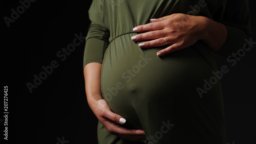 Babybauch vor schwarzem Hintergrund 