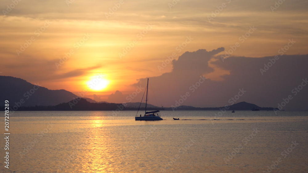 A large catamaran sails on the sea against a beautiful golden sunset. hd