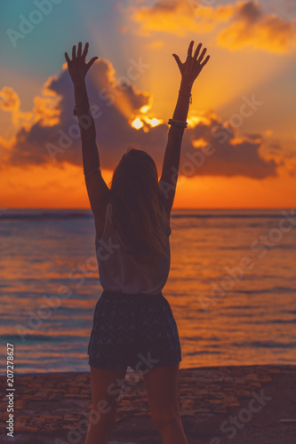 Girl with arms wide open enjoying sea   ocean scenery in sunset.