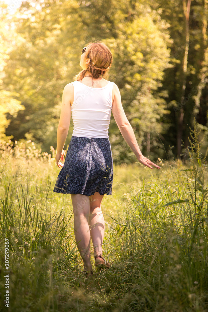 Verträumtes junges Mädchen in grüner Sommerwiese, Rock und Sonnenbrille, Aufnahme von hinten Verträumtes junges Mädchen in grüner Sommerwiese, Rock und Sonnenbrille, Aufnahme von hinten