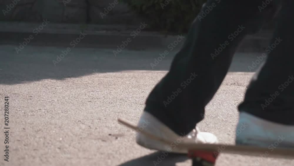 Teenager skateboarding in the street on a warm sunny day, fails at doing trick, wearing baggy black pants and white trainers, outdoor shot in urban area Teenager skateboarding in the street on a warm sunny day, fails at doing trick, wearing baggy black pants and white trainers, outdoor shot in urban area