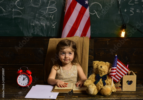 Child and demonstrating openness is must for tutor. Happy students at the lesson with USA national flag. Child needs to stay focused to finish her work. photo