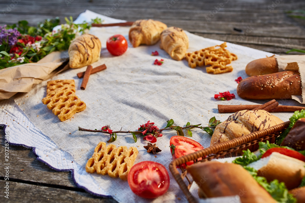 Picnic on a green lawn, pastries and vegetables on a homespun tablecloth, summer season, flat lay, selective focus