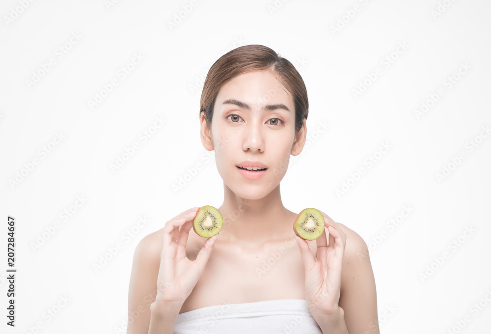 beautiful asia woman with towel on head with perfect clean skin smiling holding kiwi slices over white background. Beauty cosmetology and spa. beautiful asia woman with towel on head with perfect clean skin smiling holding kiwi slices over white background. Beauty cosmetology and spa.