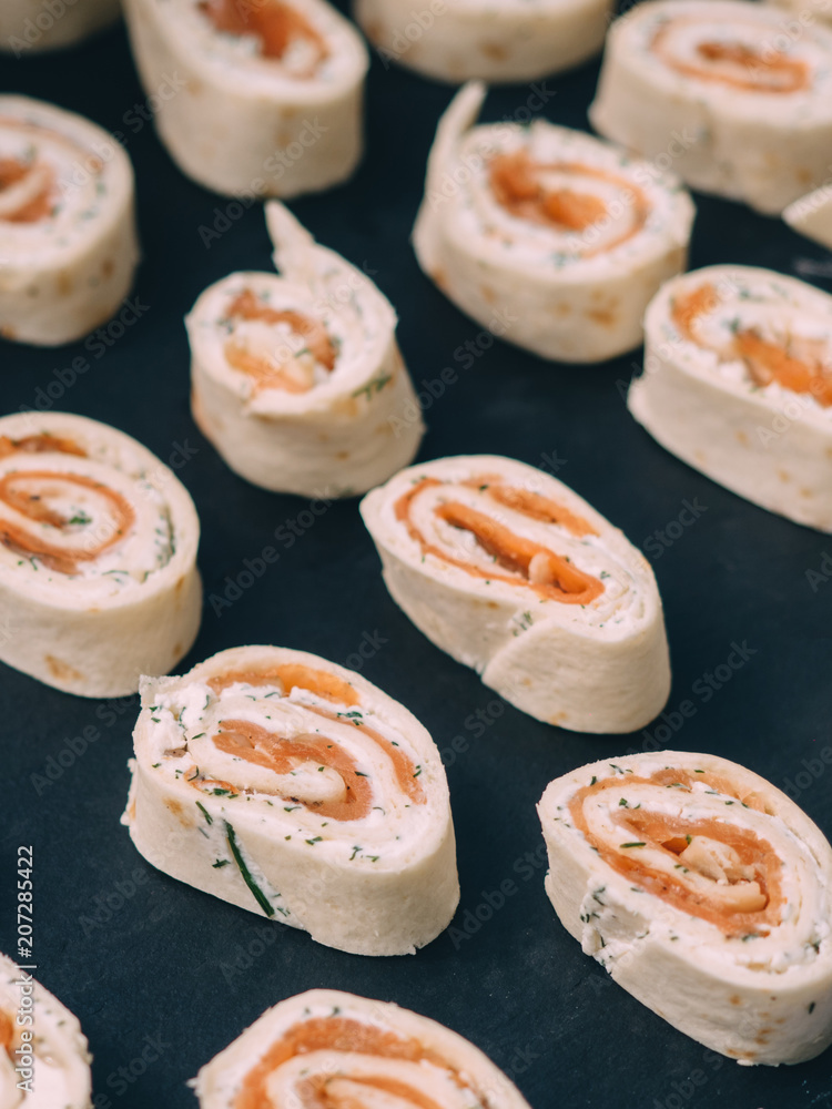 Rolls of thin pancakes with smoked salmon, horseradish cream cheese