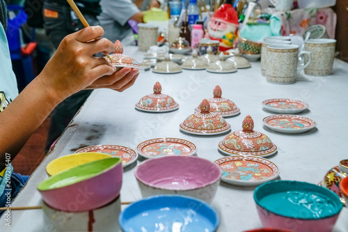 Thai women is painting Ceramic Benjarong, is traditional Thai five basic colors style pottery at Ban Don Kai Dee Samutsakorn, Thailand . Jan 21,2018.