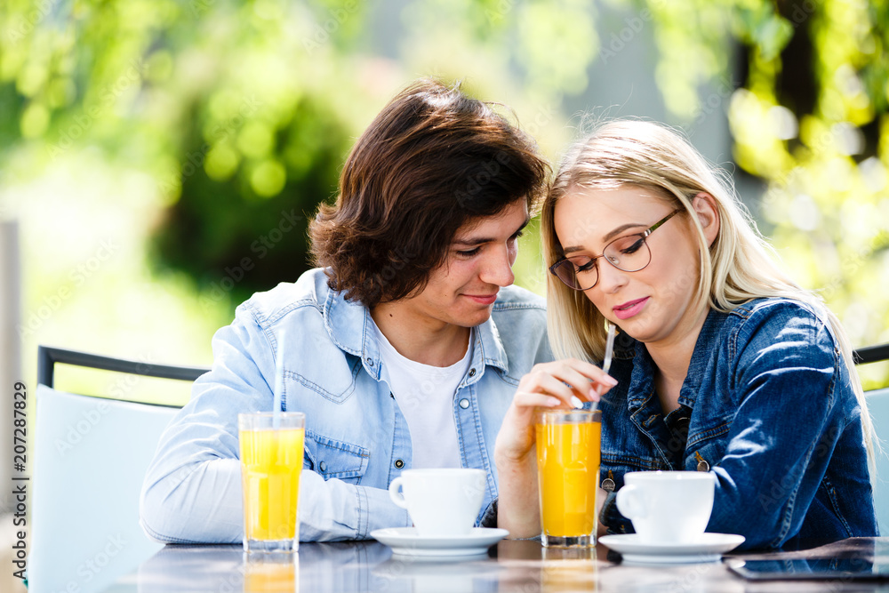 Young romantic couple spending time together - sitting in cafe's garden Young romantic couple spending time together - sitting in cafe's garden