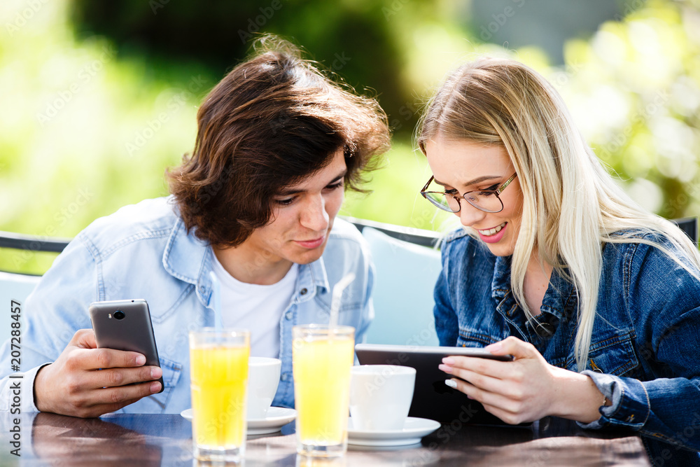 Young couple using tablet and phone while sitting together at cafe Young couple using tablet and phone while sitting together at cafe