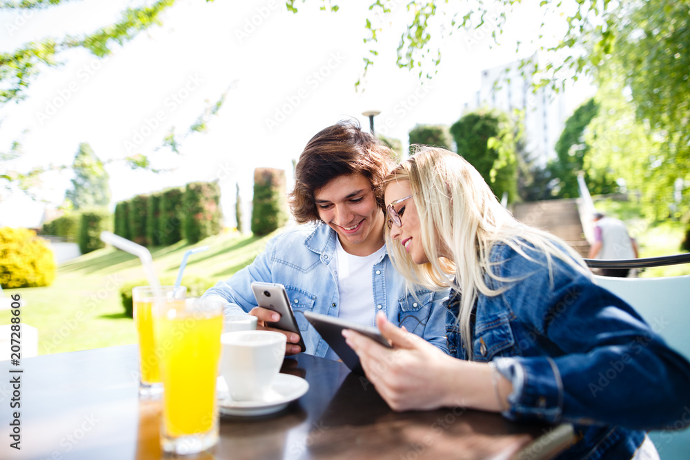 Young couple using tablet and phone while sitting together at cafe Young couple using tablet and phone while sitting together at cafe