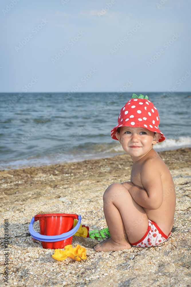 In summer, on the beach, a little girl plays with a shovel. In summer, on the beach, a little girl plays with a shovel.