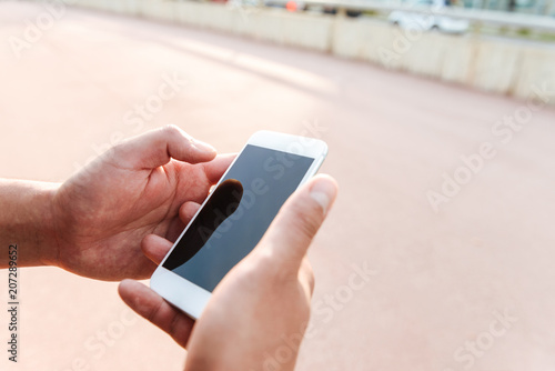 Cropped photo of young sports man using mobile phone.