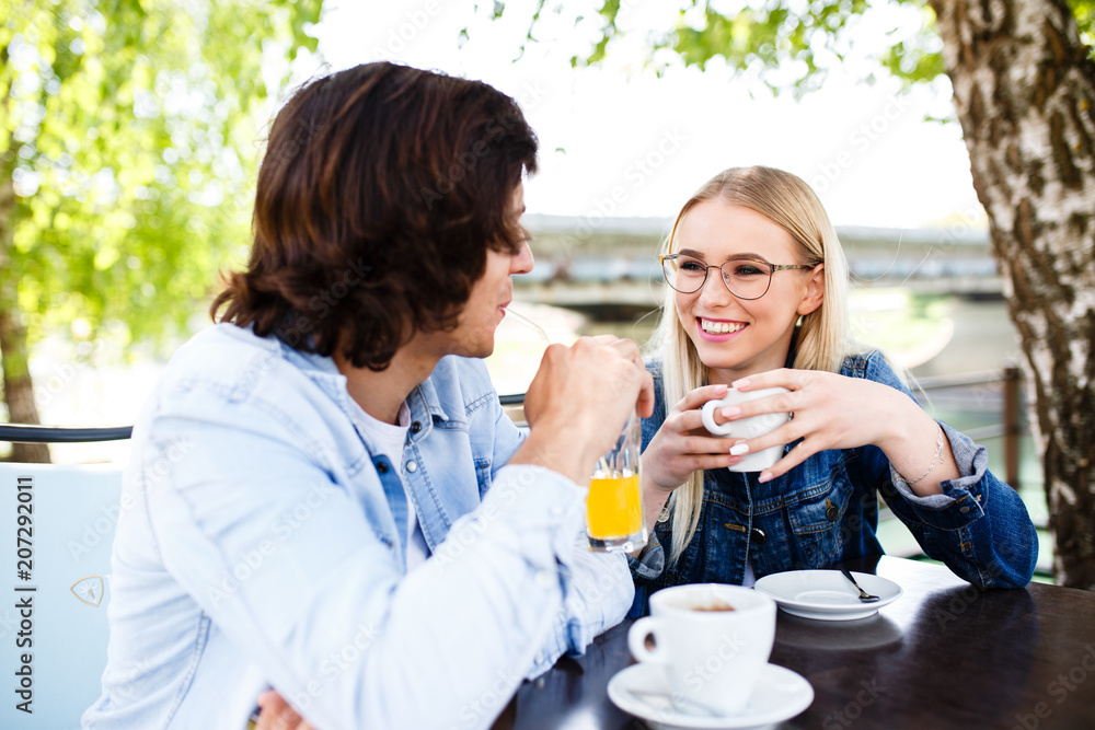 Young romantic couple spending time together - sitting in cafe's garden, drinking beverage Young romantic couple spending time together - sitting in cafe's garden, drinking beverage