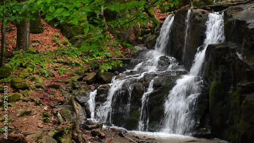 Waterfall Skakalo in deep forest. beautiful summer scenery of Carpathian nature. Wild place with huge mossy boulders, fallen trees and green foliage. front view with polarizing effect photo