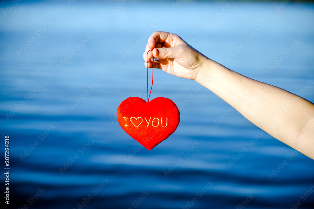 A girl holds over the water, a romantic symbol of the heart A girl holds over the water, a romantic symbol of the heart