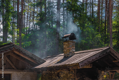 Backhaus mit rauchendem Schornstein im Wald photo