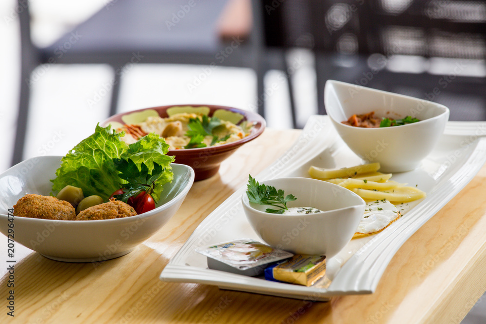 Traditional Arabic breakfast, lettuce, eggs, cheese, olives, and decorative vegetables, served on a plate, restaurant, service Traditional Arabic breakfast, lettuce, eggs, cheese, olives, and decorative vegetables, served on a plate, restaurant, service