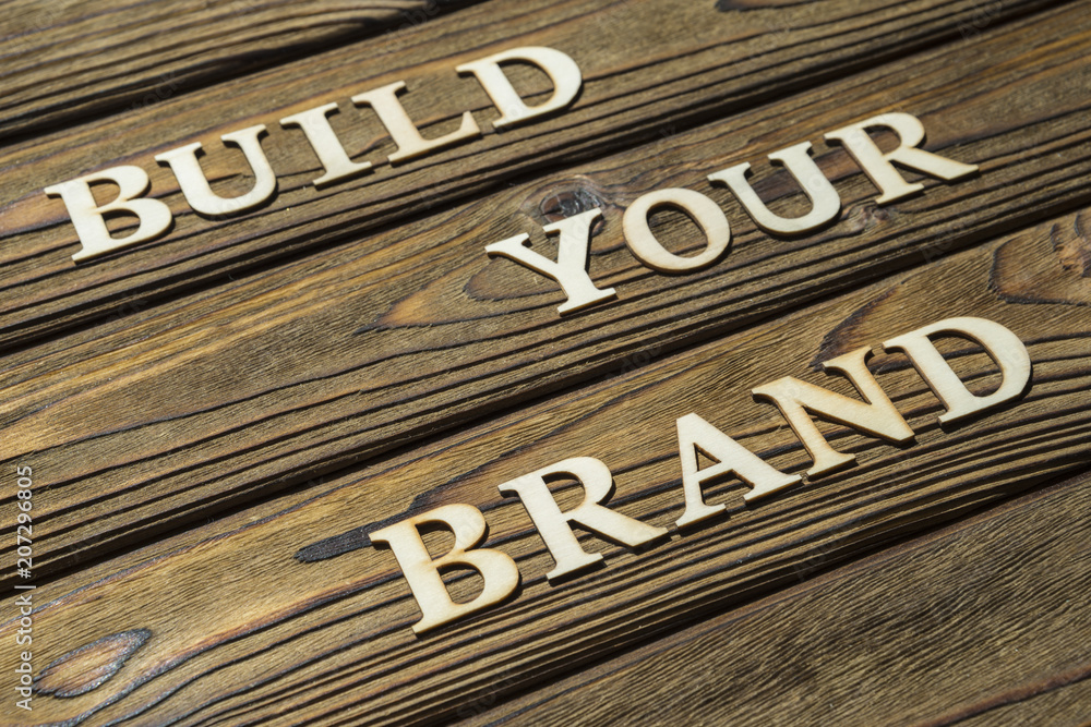Obraz premium build your brand text is composed of letters on a wooden background. The concept of business, motivation.