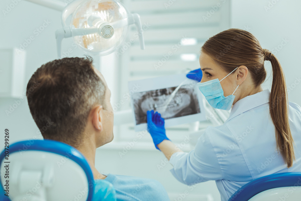 Look at this. Professional stomatologist turning head while demonstrating x-ray picture Look at this. Professional stomatologist turning head while demonstrating x-ray picture