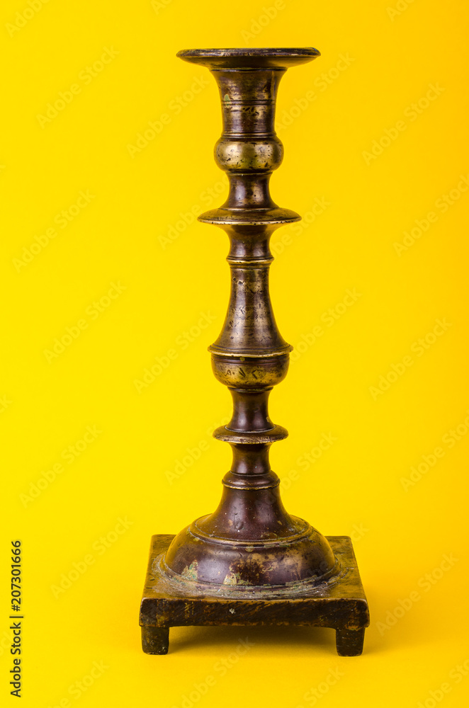 Vintage bronze candlestick on yellow background
