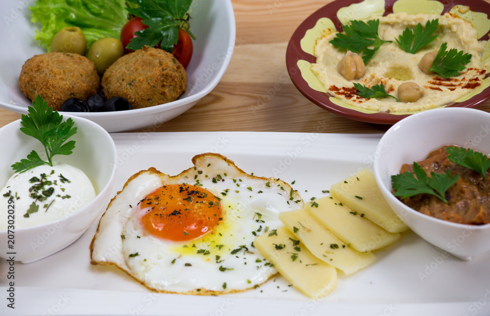 Traditional Arabic breakfast, lettuce, eggs, cheese, olives, and decorative vegetables, served on a plate, restaurant, service Traditional Arabic breakfast, lettuce, eggs, cheese, olives, and decorative vegetables, served on a plate, restaurant, service