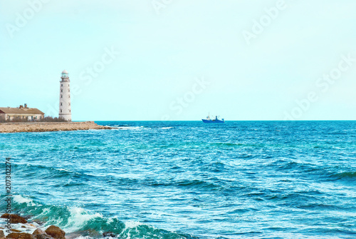 Old lighthouse on the sea coast. Storm, waves and blue sky