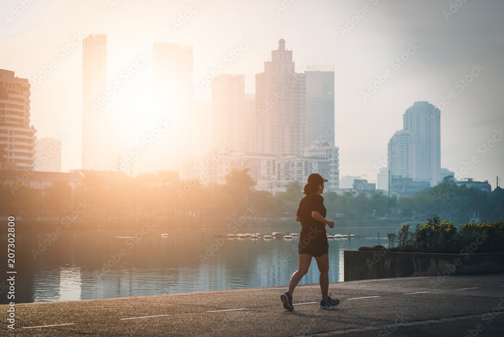Female wearing blue clothes while running in a park in the sunset. Vintage tone