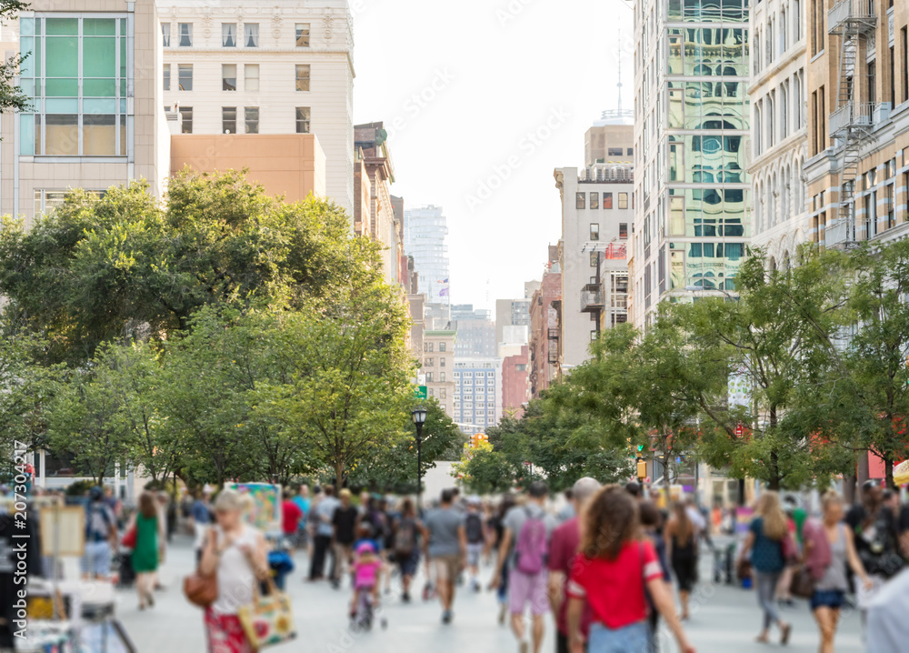 Crowds of people walking through Union Square Park in Manhattan New York City on a bright sunny day