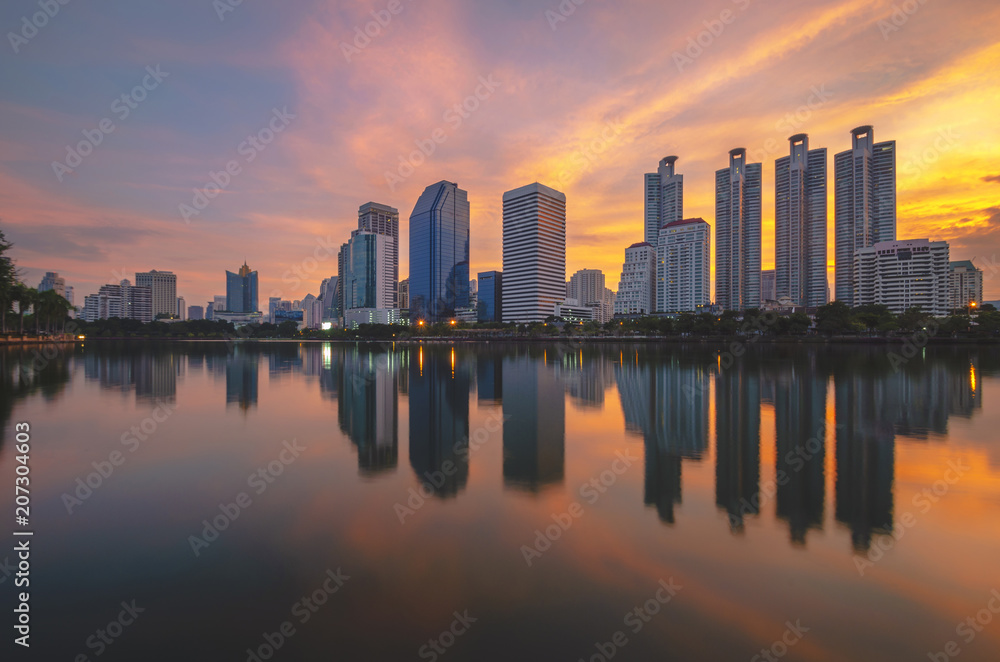 Fototapeta premium cityscapes building in modern skyline city at morning twilight golden hour with sunrise and water reflection.