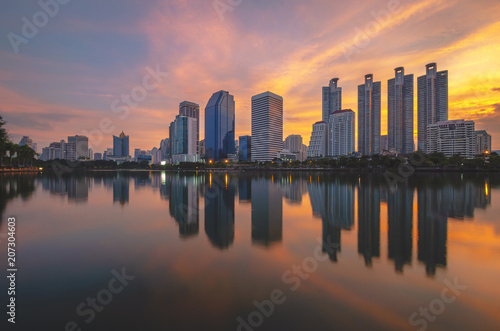 cityscapes building in modern skyline city at morning twilight golden hour with sunrise and water reflection. © thithawat
